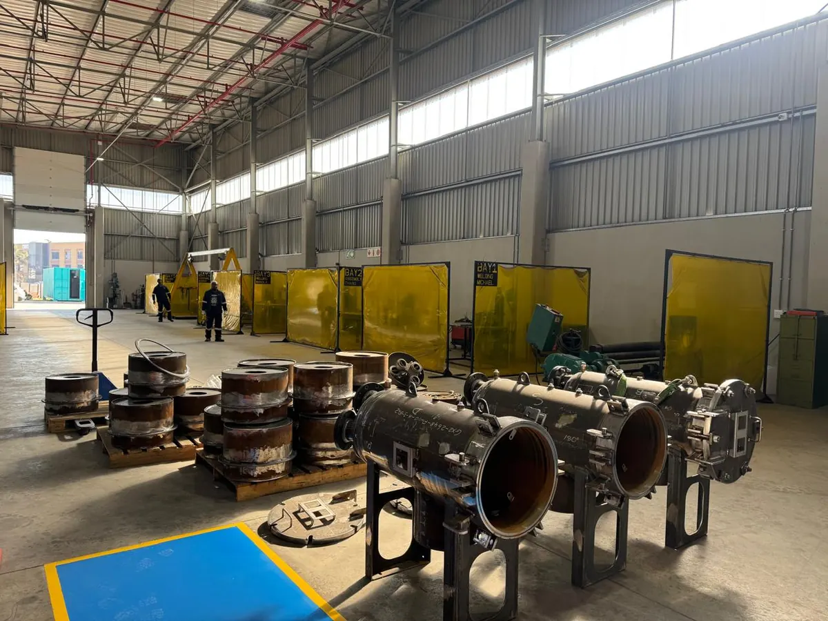 Machined filter vessel bodies and flanges laid out across the workshop floor