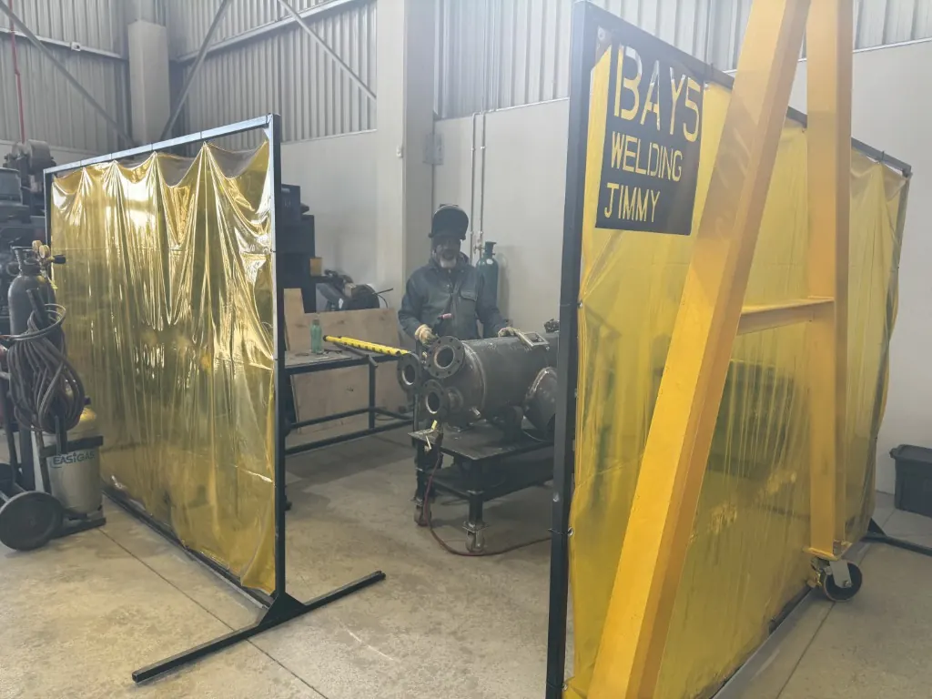 Coded welder working in a curtained welding bay on a vessel assembly